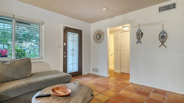 interior space featuring visible vents, a textured ceiling, baseboards, and light tile patterned flooring