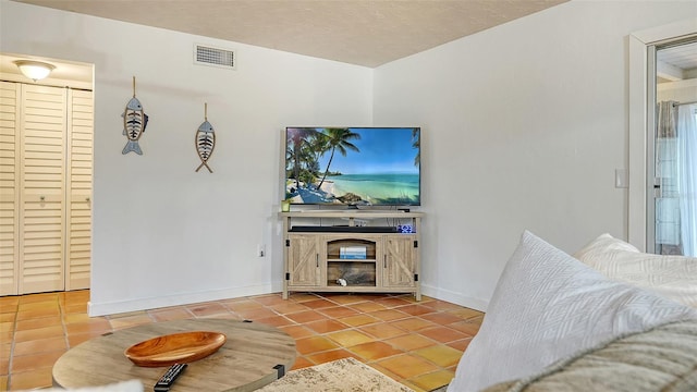 living area with visible vents, a textured ceiling, baseboards, and tile patterned floors