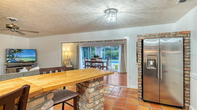 dining space featuring visible vents, a ceiling fan, a textured ceiling, and light tile patterned flooring