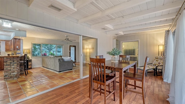 dining space featuring light wood-style flooring, beamed ceiling, wooden ceiling, and visible vents