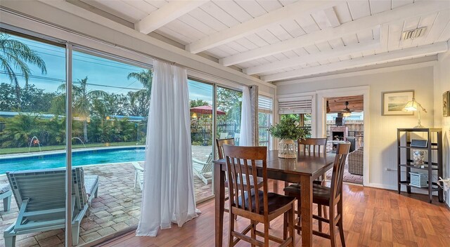 dining space featuring beamed ceiling, wood finished floors, wood ceiling, and baseboards