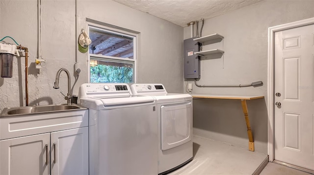 washroom featuring cabinet space, a sink, a textured ceiling, washer and dryer, and electric panel