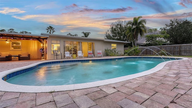 pool at dusk featuring a fenced in pool, a patio area, and fence