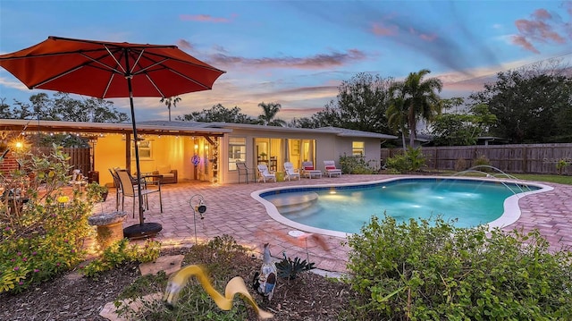 pool at dusk featuring a fenced in pool, a patio area, and fence