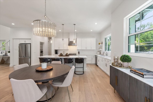 dining space with light wood-type flooring, sink, and an inviting chandelier