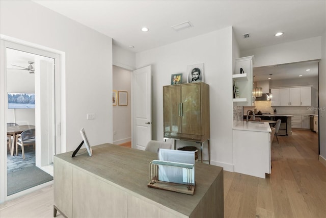 interior space featuring white cabinets, sink, tasteful backsplash, decorative light fixtures, and light hardwood / wood-style floors