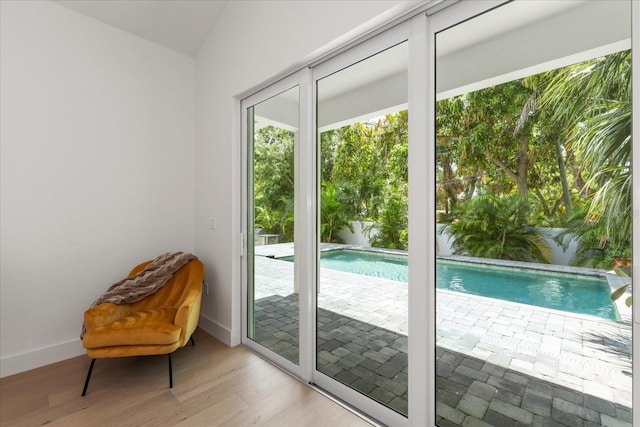 doorway to outside with vaulted ceiling and light wood-type flooring