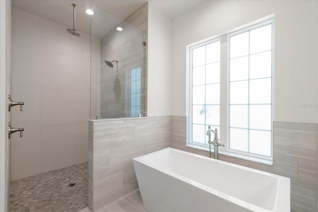 bathroom with separate shower and tub, a wealth of natural light, and tile walls