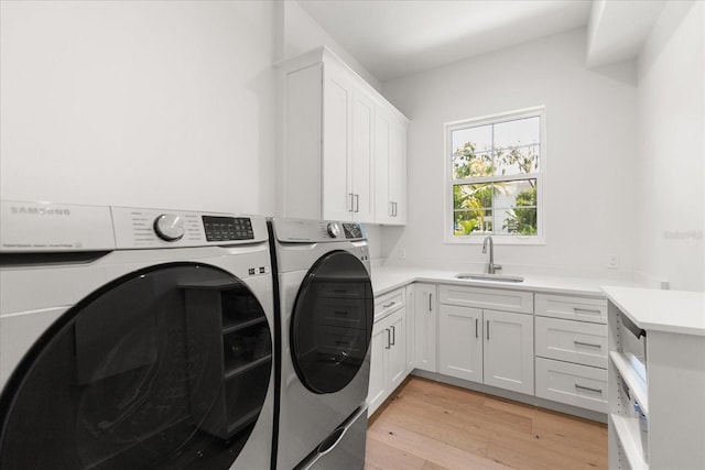 laundry area with washer and dryer, light hardwood / wood-style flooring, cabinets, and sink