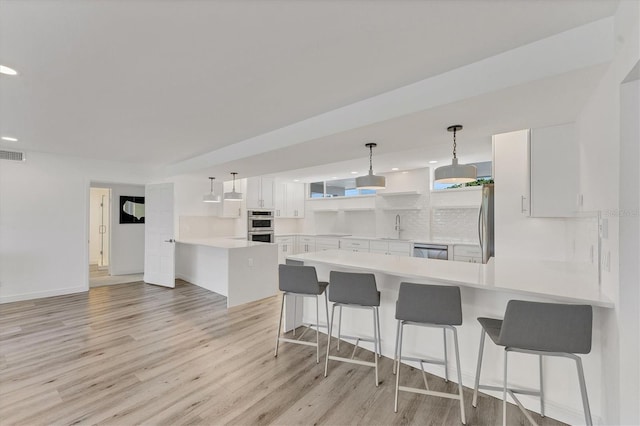 kitchen with sink, appliances with stainless steel finishes, white cabinetry, hanging light fixtures, and kitchen peninsula