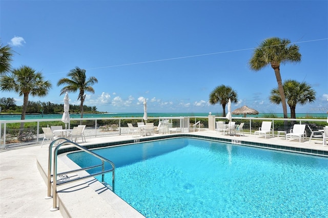 view of pool featuring a water view and a patio