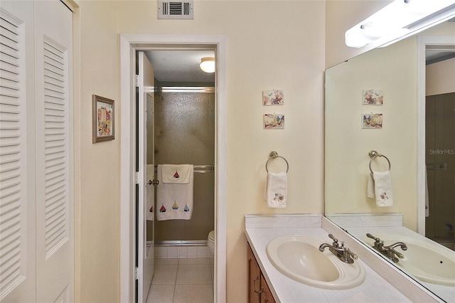 bathroom featuring tile patterned flooring, vanity, an enclosed shower, and toilet