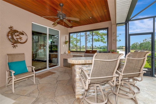 sunroom featuring ceiling fan, wood ceiling, and a wealth of natural light