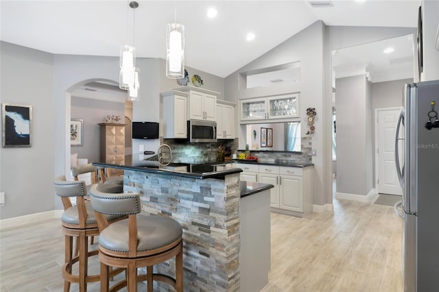 kitchen with a breakfast bar, white cabinetry, stainless steel appliances, kitchen peninsula, and hanging light fixtures