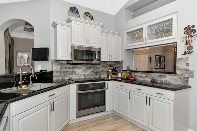 kitchen with white cabinetry, stainless steel appliances, backsplash, and sink