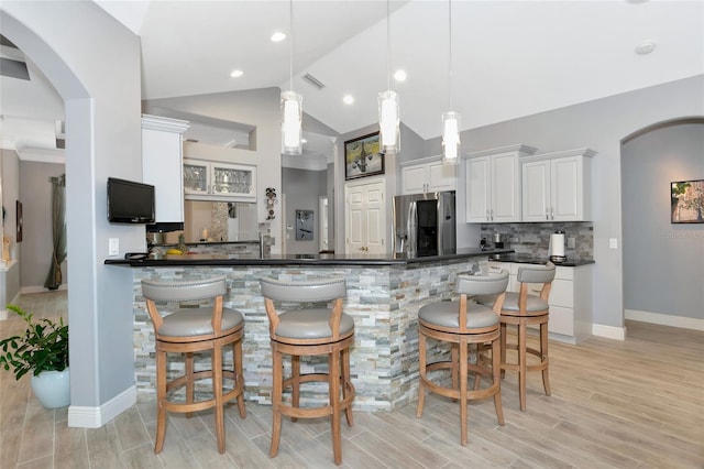 kitchen with white cabinets, stainless steel refrigerator, decorative backsplash, and decorative light fixtures