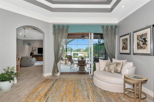 sitting room featuring a raised ceiling, hardwood / wood-style flooring, ceiling fan, and ornamental molding