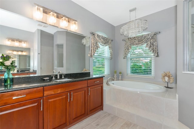 bathroom with tiled bath and vanity