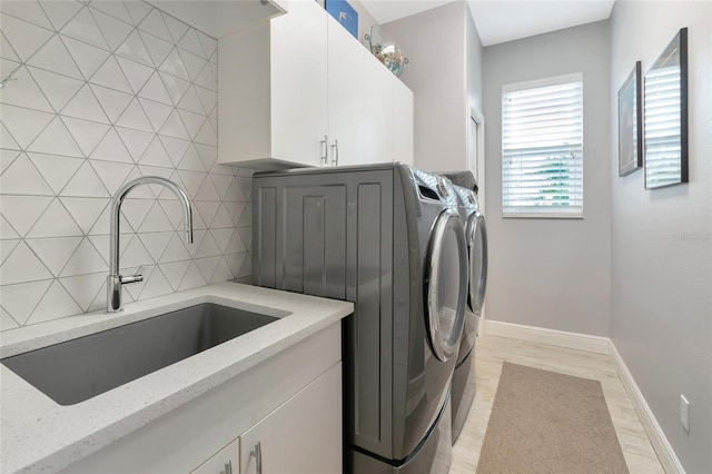 washroom with sink, cabinets, light wood-type flooring, and washer and clothes dryer