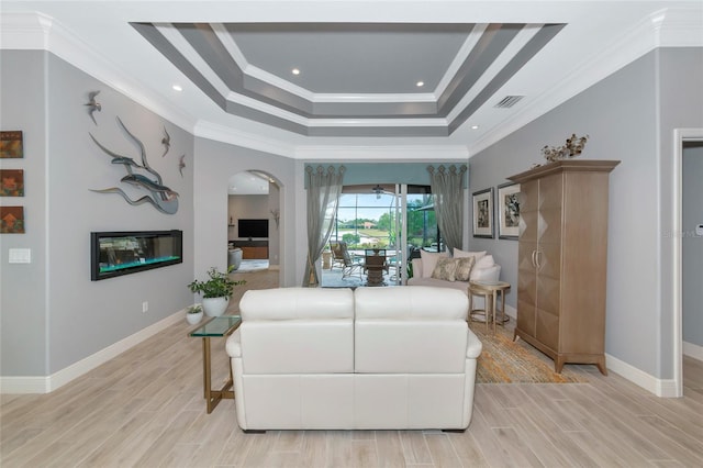 living room with light hardwood / wood-style floors, a tray ceiling, and ornamental molding