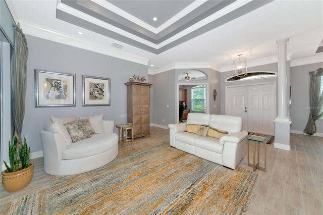 living room with a raised ceiling, light hardwood / wood-style floors, crown molding, and decorative columns