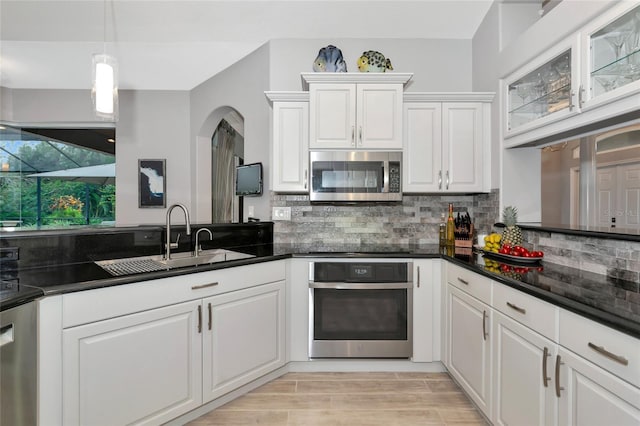 kitchen with appliances with stainless steel finishes, white cabinetry, backsplash, and sink