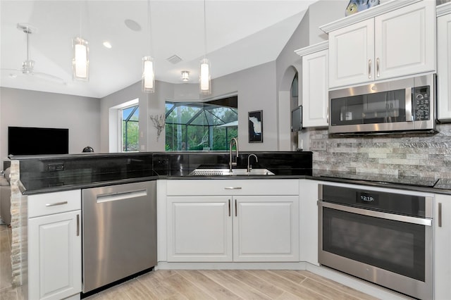 kitchen featuring decorative light fixtures, sink, stainless steel appliances, and white cabinetry