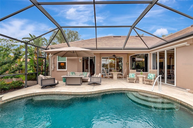 view of pool with an outdoor living space, glass enclosure, ceiling fan, and a patio area