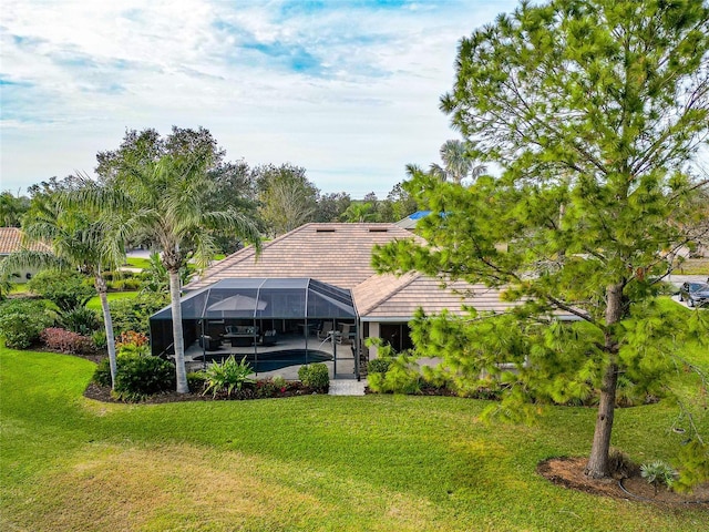 rear view of property with a yard and a lanai