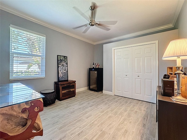 bedroom featuring crown molding, ceiling fan, light wood-style floors, baseboards, and a closet