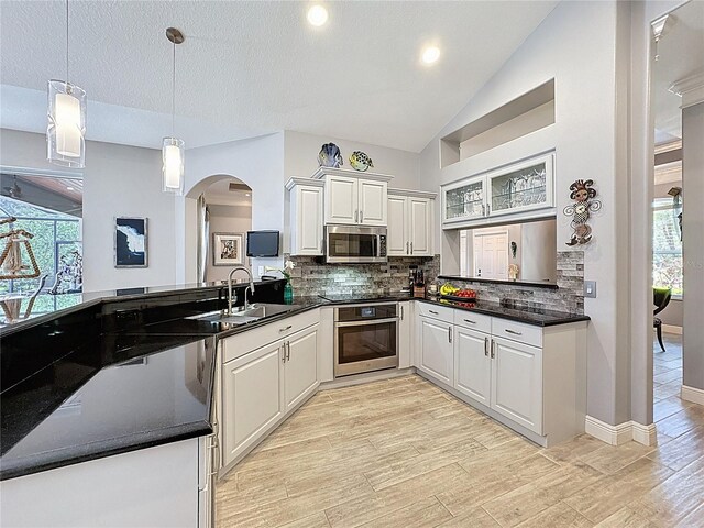 kitchen featuring arched walkways, appliances with stainless steel finishes, a wealth of natural light, and a sink
