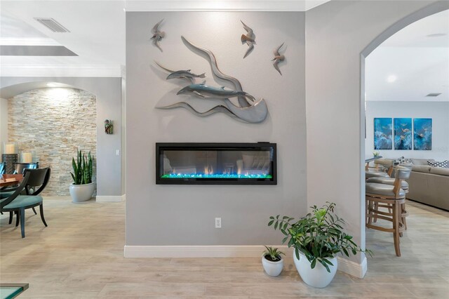 living area with visible vents, arched walkways, wood finished floors, baseboards, and a glass covered fireplace