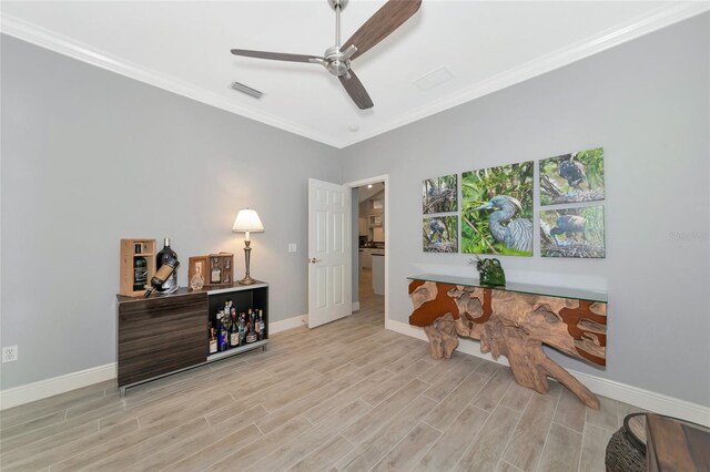 office featuring baseboards, visible vents, ornamental molding, and light wood-style flooring