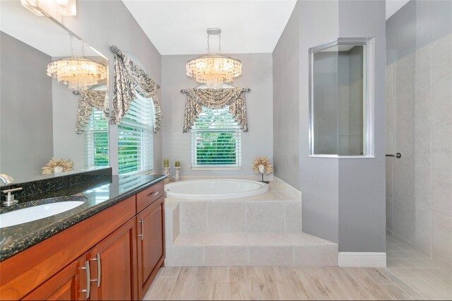full bath with vanity, walk in shower, a bath, and a notable chandelier