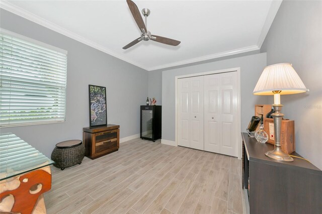 bedroom with baseboards, ornamental molding, light wood finished floors, and a closet
