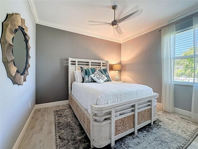 bedroom featuring crown molding, baseboards, ceiling fan, and wood finished floors