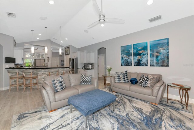 living room with visible vents, arched walkways, ceiling fan, and vaulted ceiling