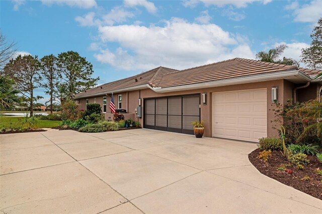 ranch-style home featuring a garage, stucco siding, driveway, and a tile roof