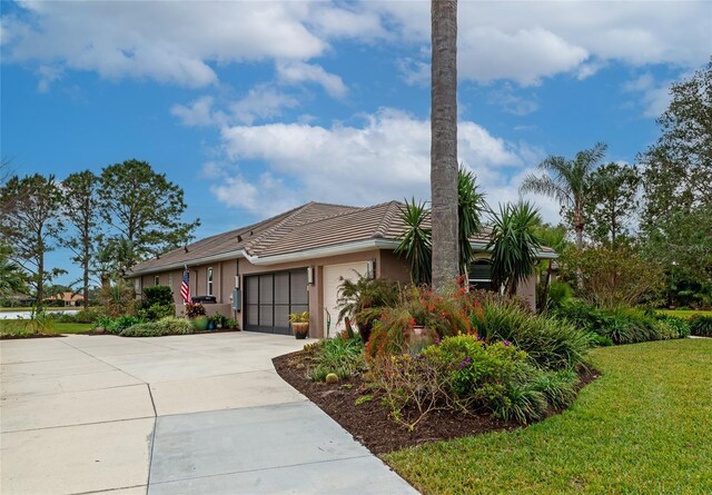 single story home with a tile roof, a front yard, concrete driveway, an attached garage, and stucco siding