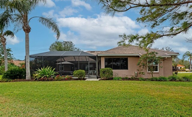 back of house with a lawn, glass enclosure, and stucco siding