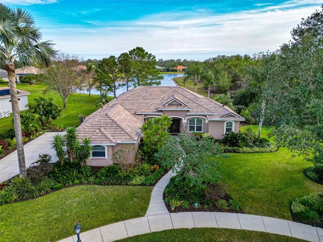 view of front of house featuring stucco siding, a tile roof, and a front yard