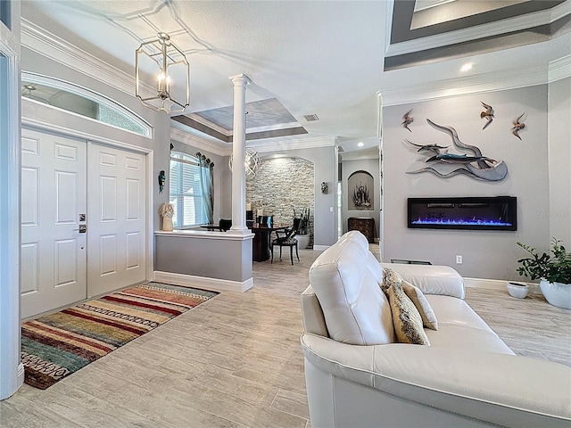 16806 5th Ter NE, Bradenton, FL 34212 - foyer featuring crown molding, decorative columns, a glass covered fireplace, a chandelier, and wood finished floors