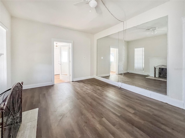 unfurnished living room with ceiling fan and dark wood-type flooring