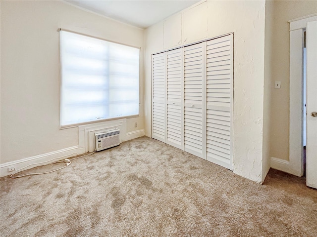 unfurnished bedroom with a wall unit AC, a closet, and light colored carpet