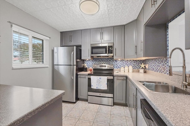 kitchen featuring appliances with stainless steel finishes, sink, light tile patterned floors, and decorative backsplash