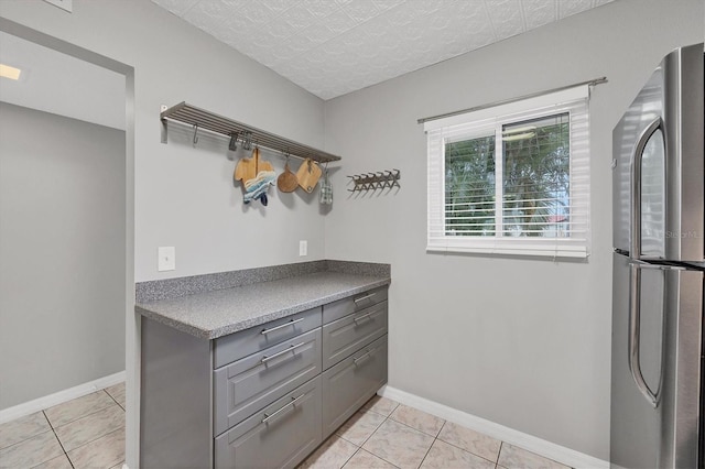 kitchen featuring stainless steel refrigerator, gray cabinets, and light tile patterned flooring