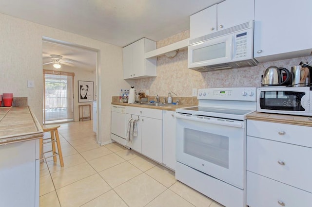 kitchen featuring ceiling fan, sink, light tile patterned floors, white appliances, and white cabinets