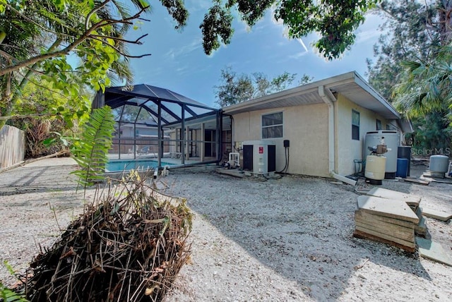 rear view of property featuring a fenced in pool and glass enclosure