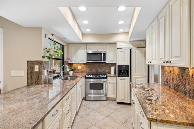 kitchen featuring light stone counters, sink, decorative backsplash, and appliances with stainless steel finishes