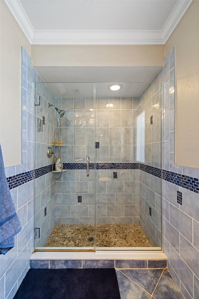 bathroom with ornamental molding and a shower with shower door